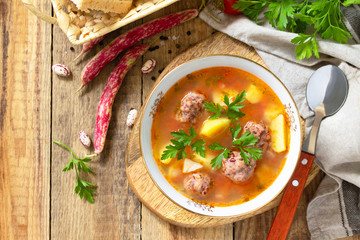 The concept of healthy and diet food, vegetarian dish. Delicious Vegetable soup with bean balls on a rustic table. Top view flat lay background. Copy space.