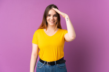 Young caucasian woman isolated on purple background saluting with hand with happy expression