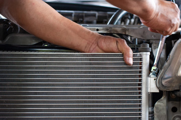 Hands of mechanic working in auto repair shop; check the car radiator - 329794432