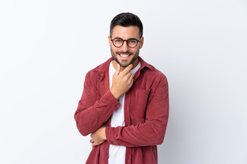 Young handsome man with beard wearing a corduroy jacket over isolated white background with glasses and smiling