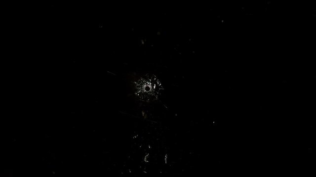 Shot Glass breaking with bullet holes on black background