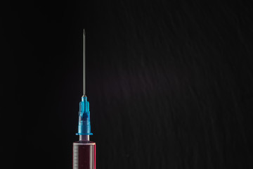 syringe with red medicine on a dark background. Close-up. The full length of the medical needle. copy space