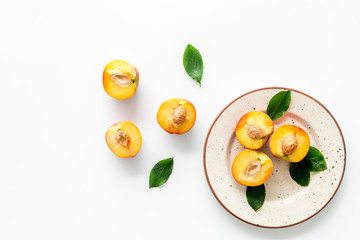 Healthy food. Ripe sliced peaches on plate on white table top-down