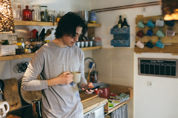 man using mobile phone in kitchen. morning scene