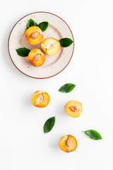 Peaches pattern with plate and leaves on white table top-down