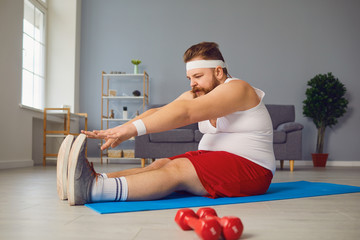Funny red fat man doing exercises on the floor while standing at home.