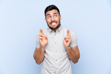 Fototapeta premium Young handsome man with beard over isolated blue background with fingers crossing