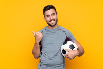 Football player man over isolated background pointing to the side to present a product © luismolinero