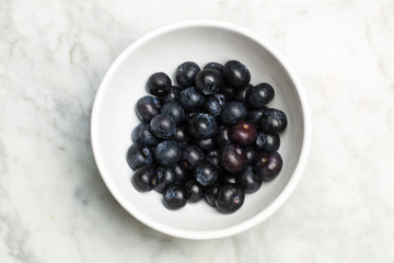 Arándanos dentro de un cuenco blanco sobre una mesa de mármol. Vista superior