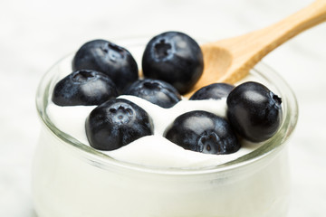 Arándanos en un cuenco con yogur natural y cuchara de madera. Vista superior y de cerca