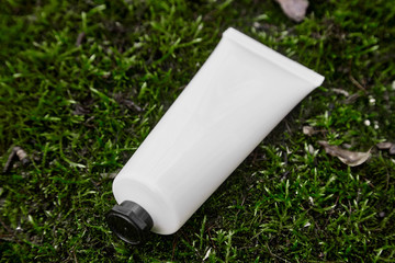 Tube of cream on dark background made of moss