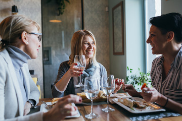women friends having lunch break in restaurant, making a toast