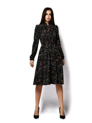 Young brunette woman model with long straight hair in stylish vintage dark midi dress and high-heel shoes is posing