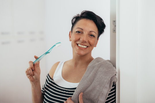 woman holding tooth brush and towel at home