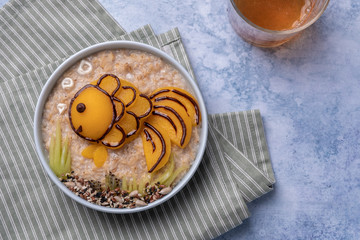 Kids breakfast oatmeal porridge with fruit look like a golden fish