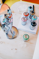 spray cans on a wooden table are reflected in a table mirror