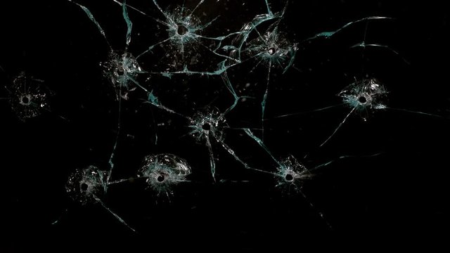 Shot Glass breaking with bullet holes on black background