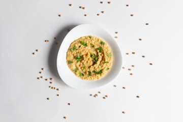 Hummus with parsley in plate on white background with chickpeas