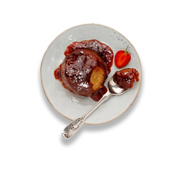 An individual strawberry sponge cake, with a sticky strawberry sauce, on a white plate with a spoon, isolated on white with a darop shadow.