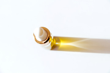 cosmetic oil in glass bottle with white pipette on white background with copy space