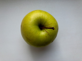One green Apple is on the table. The view from the top.