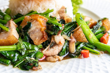 Crispy pork with Chinese kale with steamed rice and fried egg on a white plate.