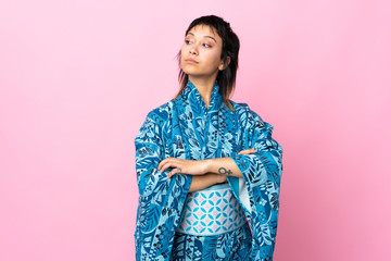 Young woman wearing kimono over isolated blue background keeping the arms crossed