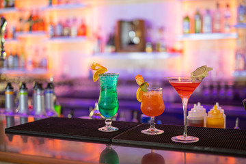 Colorful cocktails on the bar counter, party night out background. Cocktails drinks on the bar