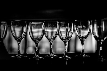 Rows of empty wine glasses on the showcase, black and white photography
