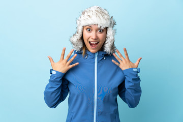 Young Uruguayan girl with winter hat isolated on blue background with surprise facial expression