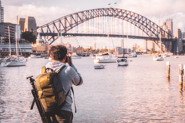 Reiziger man jonge backpacker die staat en een professionele spiegelloze DSLR-camera gebruikt, maakt een prachtige foto van de skyline van Sydney met de noordkust van de Sydney Harbour Bridge in Australië.