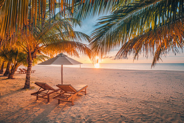 Prachtig tropisch zonsonderganglandschap, twee ligbedden, ligstoelen, parasol onder palmboom. Wit zand, uitzicht op zee met horizon, kleurrijke schemerhemel, rust en ontspanning. Inspirerend strandresorthotel