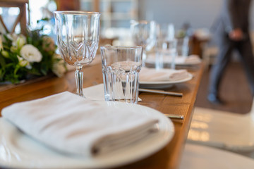 Glasses, forks, knives, plates on a table in restaurant served for dinner. Set dining table in loft style