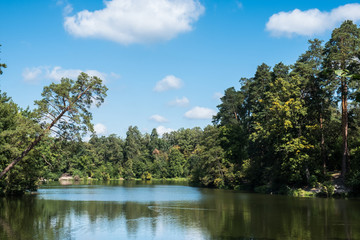 Scenic view of the park in the center of the big city in the summer. With a lagoon in the middle and green trees. In the atmosphere of evening light