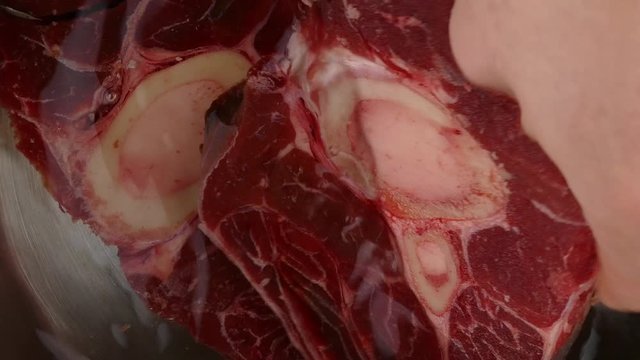 putting fresh beef shanks into a pot with water to cook a beef stock closeup 4k