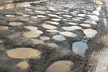 Pits on a gravel road with mud and puddles in spring in Russia