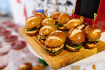 Mini Chicken Burger on wooden chopping board with blur background.