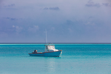 Fototapeta premium Small fishing boat and ship in front of beautiful seascape scenery and blue sky at Maldives island. Traditional and way of life concept.