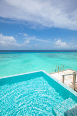 Minimalist infinity pool in tropical paradise beach. Luxury resort travel background. Blue sea view...