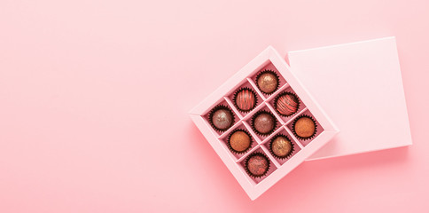 Chocolate truffle candies in a box pink background. Gifts festive food love concept. Horizontal...