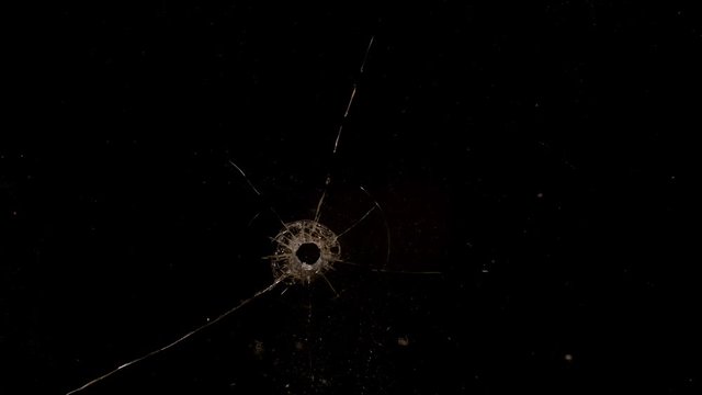 Shot Glass breaking with bullet holes on black background
