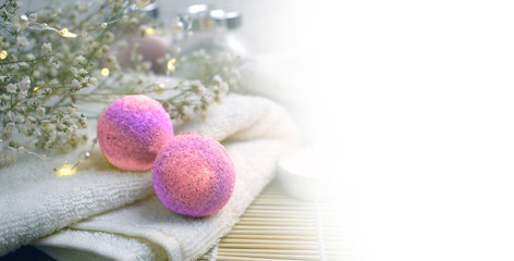 Mock up spa resort setting. Still life image with bath bombs, flowers, scrub, towel on wooden background. Spring or summer relax concept.