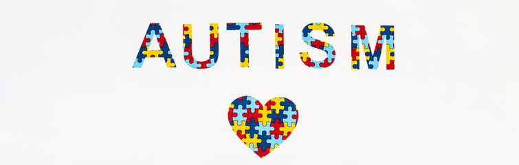 Top view of puzzle heart an Autism lettering isolated on white, panoramic shot