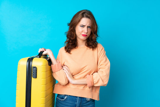 Traveler woman with suitcase over isolated blue background thinking an idea