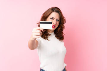 Young Russian woman over isolated pink background holding a credit card