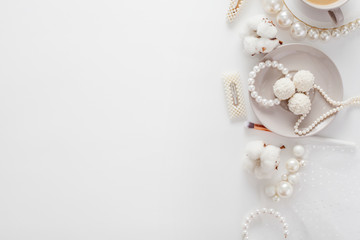 Wedding composition top view, decorated with pearl jewelry, coconut candy, cotton flower, coffee, hairpins, makeup brush, all in pastel soft colors. Concept morning of the bride.