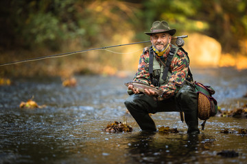Close-up view of the hands of a fly fisherman holding a lovely trout while  fly fishing on a...