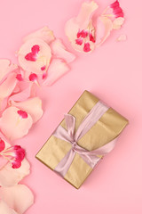 Floral frame with gold gift box on pink background. Greetings concept