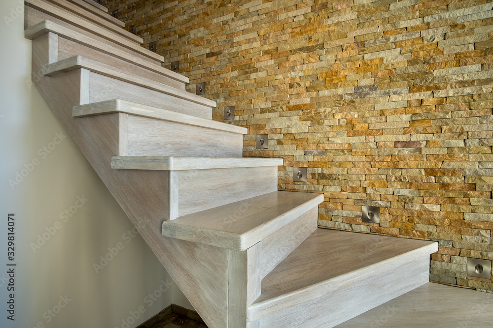 Sticker Stylish wooden contemporary staircase inside loft house interior. Modern hallway with decorative limestone brick walls and white oak stairs.