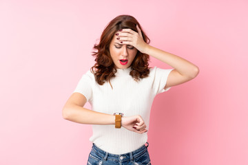 Young Russian woman over isolated pink background with wrist watch and surprised